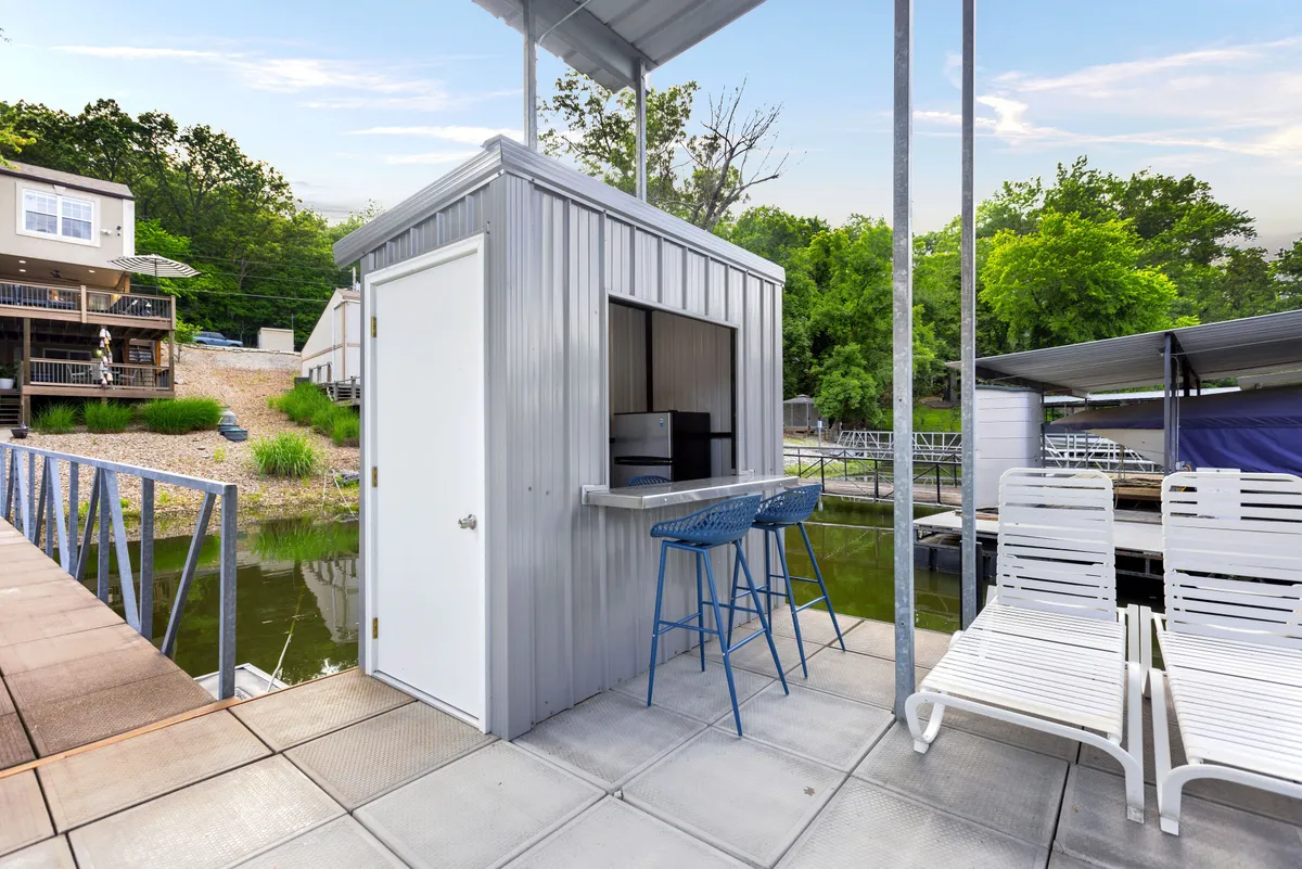 A lively dockside kiosk with bar stools, lounge chairs, and lush greenery. The setup is perfect for relaxing with drinks after a swim or enjoying casual conversation by the water, reinforcing the sense of a private resort experience.