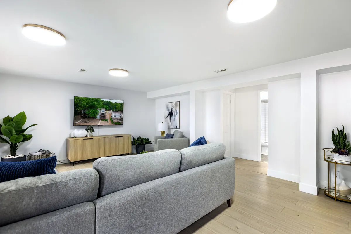 This image showcases a comfortable living area with a plush sofa, television, plant, and side table. The setup is perfect for family movie nights or relaxing together after a day on the lake. The decor is modern yet cozy, inviting guests to gather and unwind.