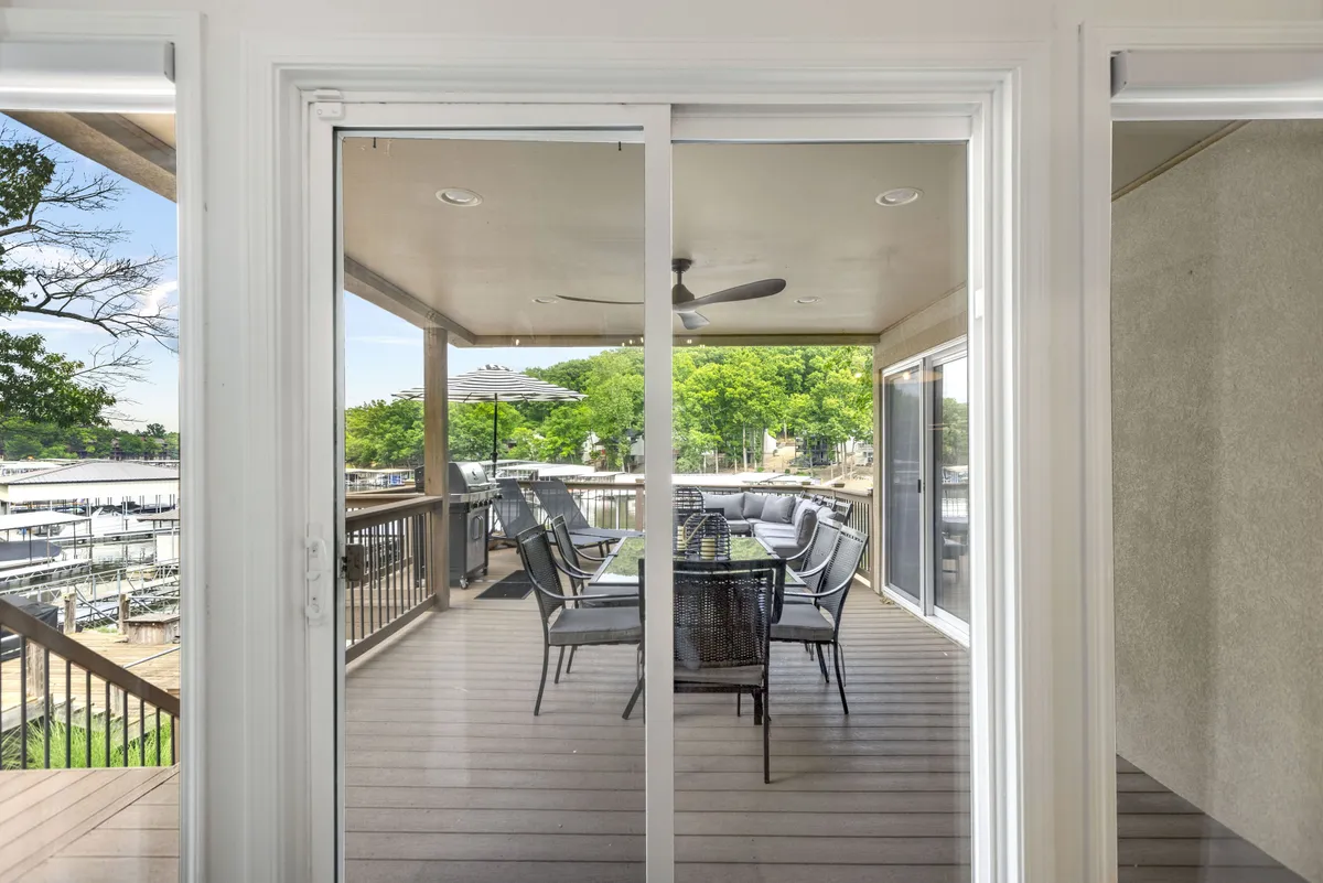 An outdoor dining area on a deck overlooking the marina, complete with a dining table and chairs. The setting is framed by trees and open to the water, perfect for al fresco meals and social gatherings.