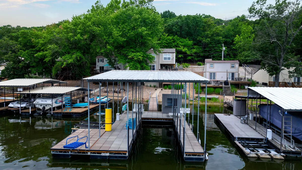 This exterior image captures the private boat docks surrounded by lush greenery and peaceful houses in the background. The scene hints at the calm cove waters mentioned in the section, and suggests opportunities for boating, fishing, and relaxing right at the water’s edge.